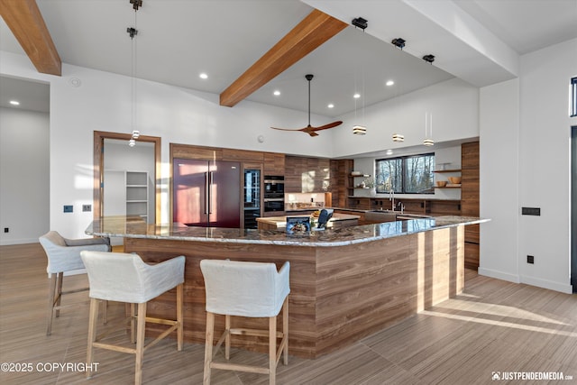 kitchen featuring sink, dark stone countertops, beamed ceiling, decorative light fixtures, and stainless steel appliances