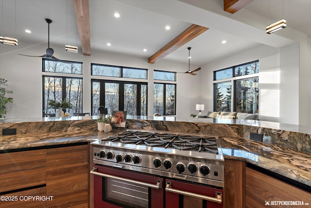 kitchen featuring beamed ceiling, ceiling fan, dark stone countertops, and high end stainless steel range