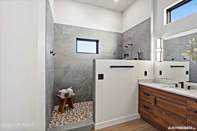 bathroom with a tile shower, vanity, hardwood / wood-style flooring, and a wealth of natural light