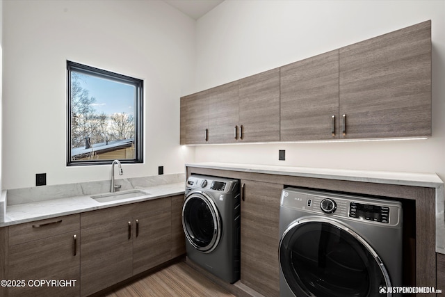 washroom featuring cabinets, washing machine and dryer, light hardwood / wood-style floors, and sink