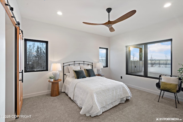 bedroom with a barn door, ceiling fan, and light colored carpet