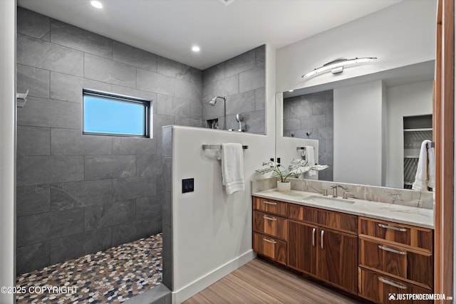 bathroom featuring tiled shower, hardwood / wood-style floors, and vanity