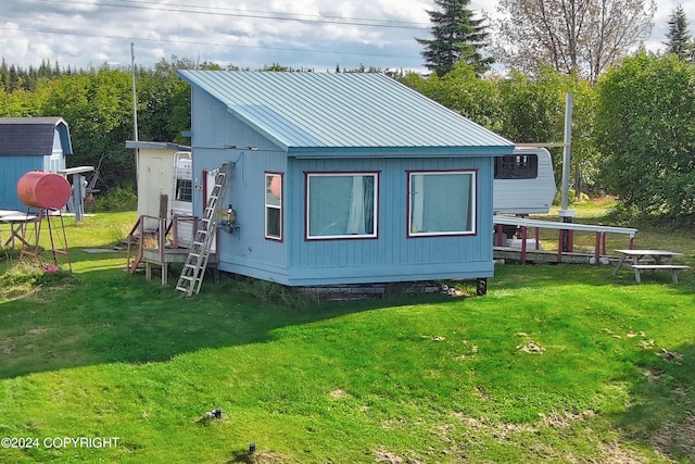 back of house featuring a storage shed and a yard