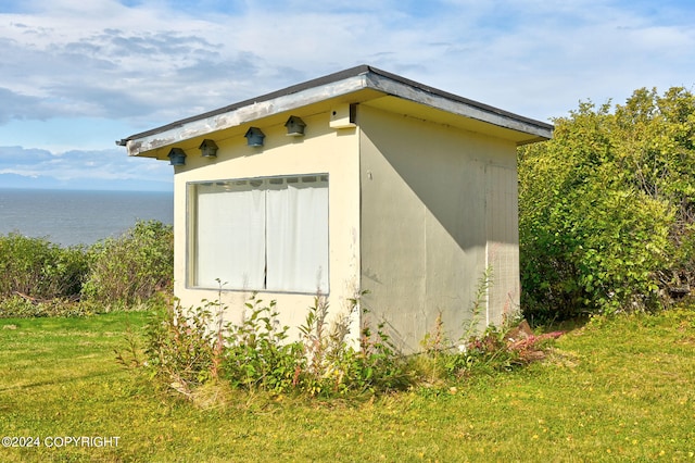 view of outdoor structure featuring a lawn and a water view