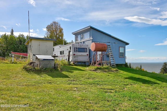 rear view of property featuring a water view, a shed, and a yard