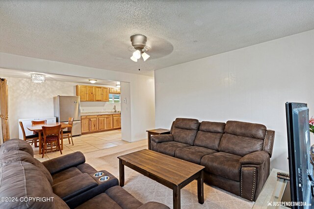 tiled living room with a textured ceiling, sink, and ceiling fan