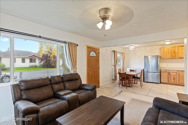 living room featuring a textured ceiling, light tile patterned floors, and ceiling fan