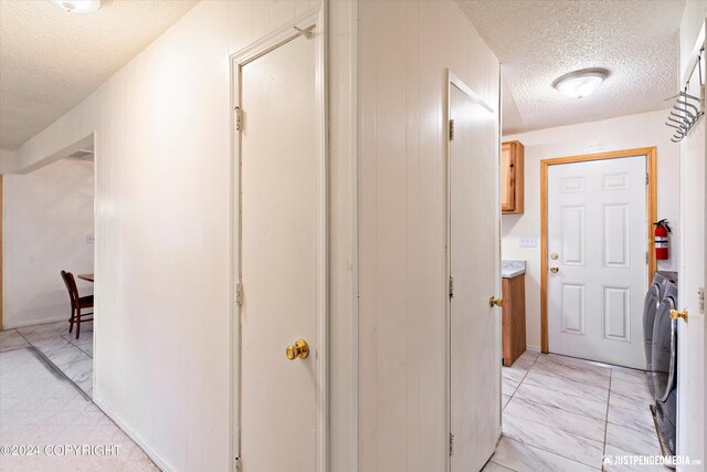 hallway with washer and clothes dryer and a textured ceiling