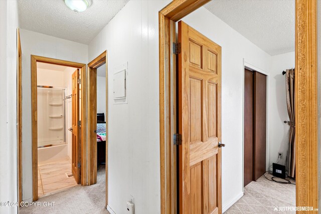 corridor featuring a textured ceiling and light carpet