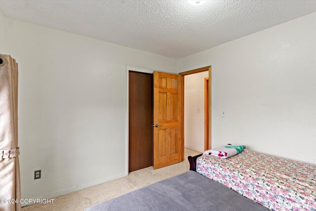 unfurnished bedroom with a textured ceiling and light colored carpet