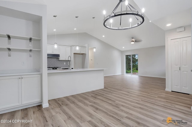 kitchen featuring white cabinets, lofted ceiling, hanging light fixtures, a chandelier, and light hardwood / wood-style floors