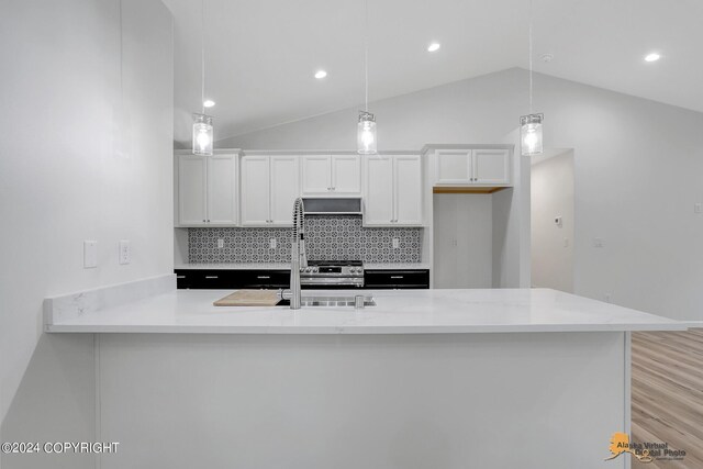 kitchen featuring hanging light fixtures, vaulted ceiling, and white cabinetry