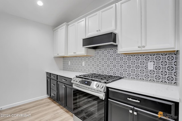 kitchen featuring white cabinets, stainless steel gas range oven, backsplash, and light hardwood / wood-style floors