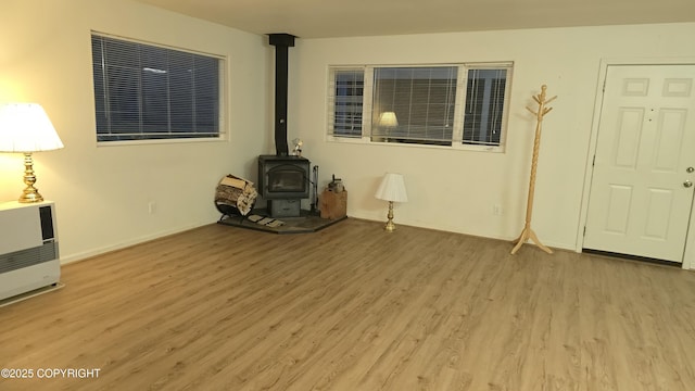 unfurnished living room featuring light hardwood / wood-style floors and a wood stove