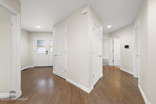 hallway featuring baseboards, dark wood finished floors, and recessed lighting