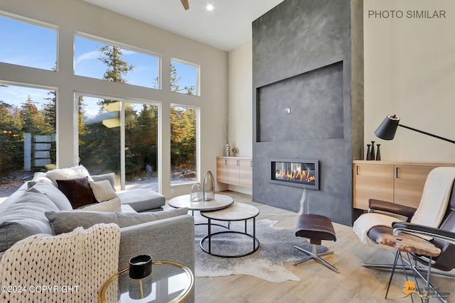 living room with a large fireplace, light hardwood / wood-style floors, and a high ceiling