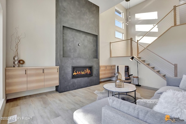 living room featuring a towering ceiling, light hardwood / wood-style floors, and a fireplace