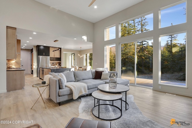 living room featuring a high ceiling, sink, and light hardwood / wood-style flooring