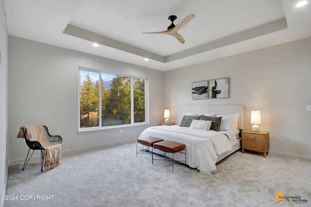 bedroom with light colored carpet, ceiling fan, and a raised ceiling