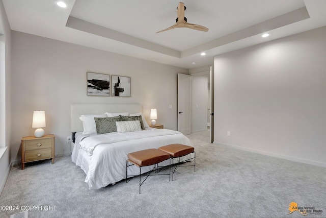 carpeted bedroom with ceiling fan and a raised ceiling