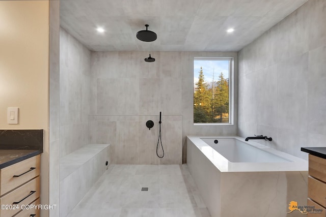 bathroom featuring plus walk in shower, tile walls, and vanity