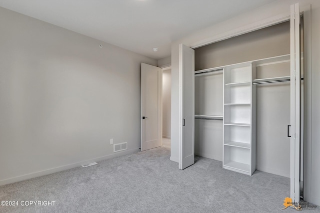 unfurnished bedroom featuring a closet and light colored carpet