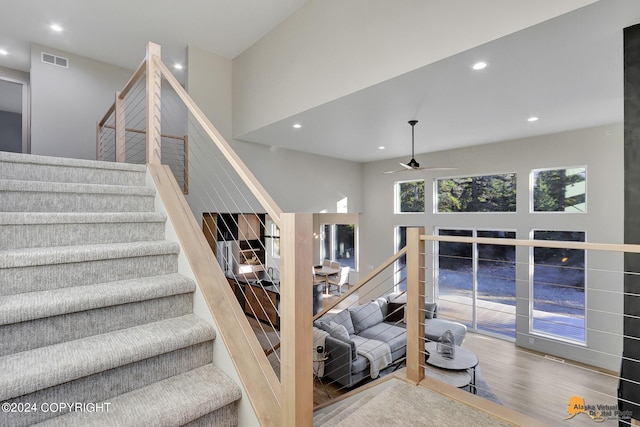 staircase with wood-type flooring and ceiling fan