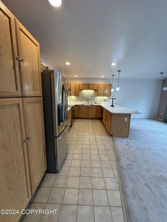 kitchen featuring pendant lighting, stainless steel appliances, decorative backsplash, and light colored carpet