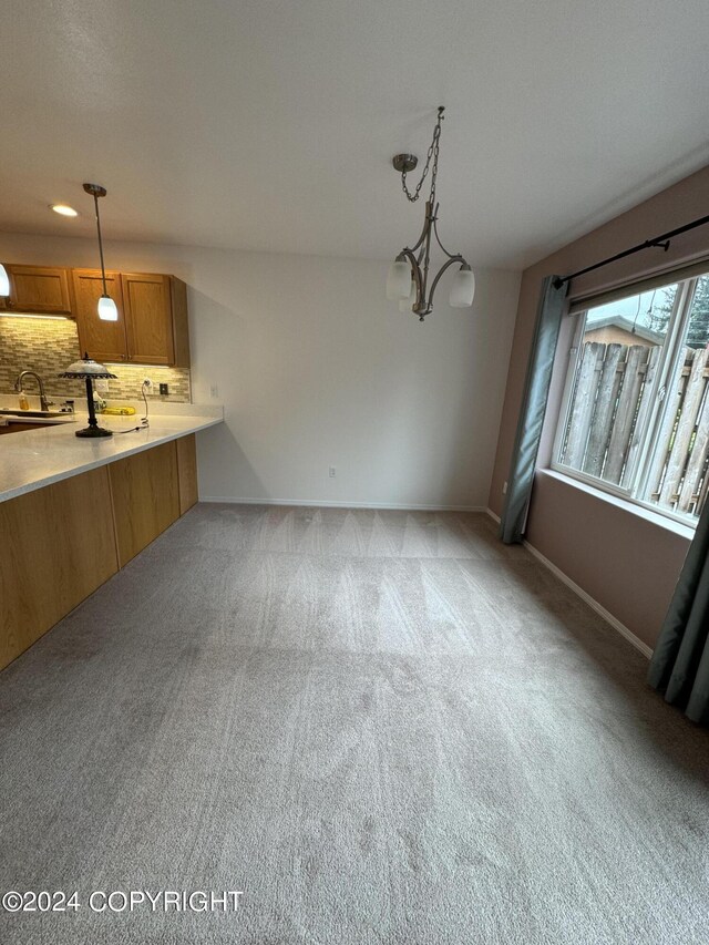 kitchen featuring light colored carpet, an inviting chandelier, decorative light fixtures, and tasteful backsplash