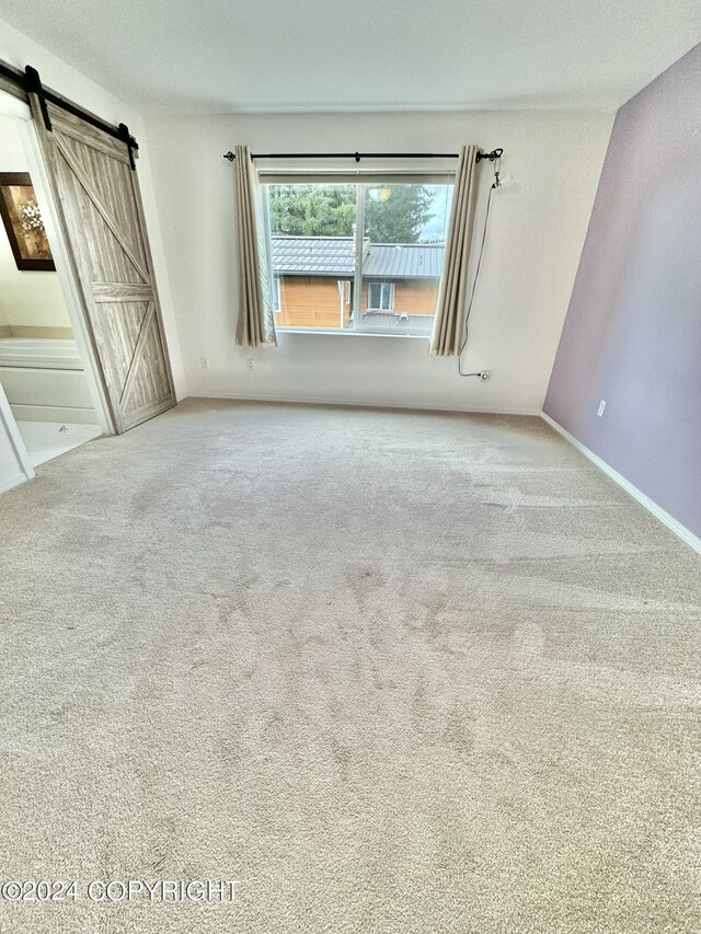 unfurnished room with carpet and a barn door