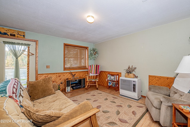 living room with a textured ceiling, light hardwood / wood-style floors, and wooden walls