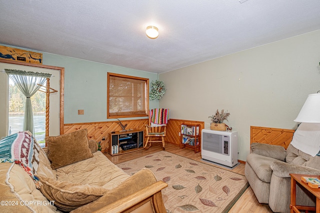 37325 Funny Moose Ln, Soldotna, AK 99669 - living area with light wood-style flooring, heating unit, wainscoting, wood walls, and a textured ceiling