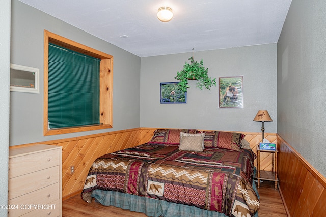 bedroom with wooden walls and light hardwood / wood-style flooring