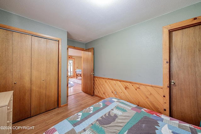 37325 Funny Moose Ln, Soldotna, AK 99669 - bedroom featuring wood finished floors, a closet, a wainscoted wall, wood walls, and a textured ceiling