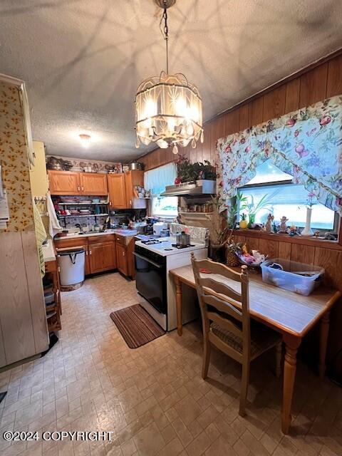 716 Thorsheim St, Kodiak, AK 99615 - kitchen with wooden walls, a textured ceiling, range with electric stovetop, brown cabinetry, and an inviting chandelier