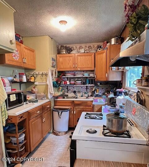 kitchen featuring range hood, a textured ceiling, sink, and white range with electric stovetop