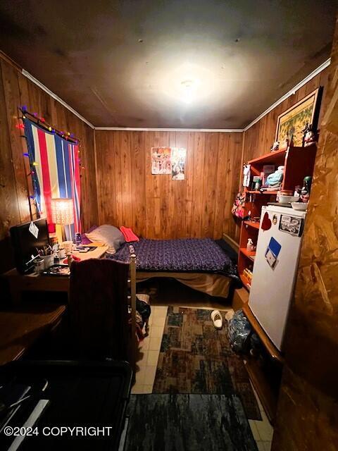 bedroom featuring wooden walls and white fridge