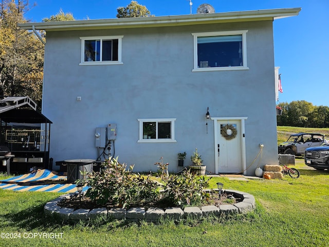 back of property featuring a lawn and stucco siding