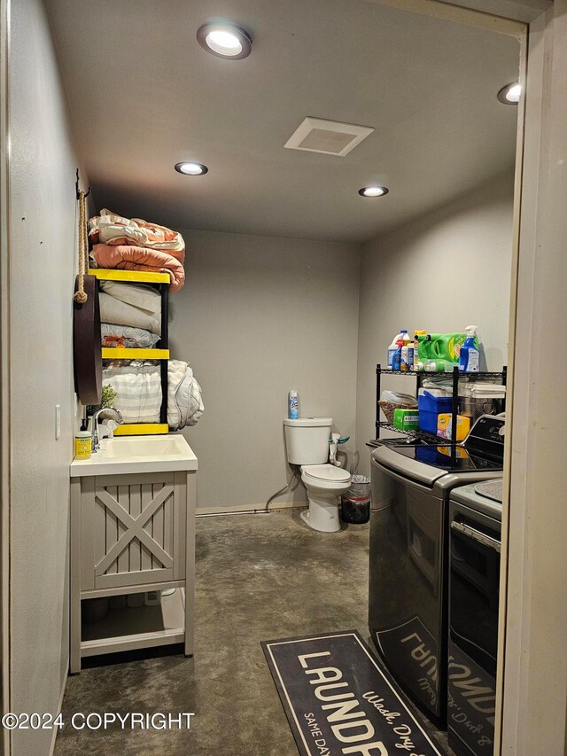 bathroom with toilet, concrete floors, separate washer and dryer, a sink, and recessed lighting