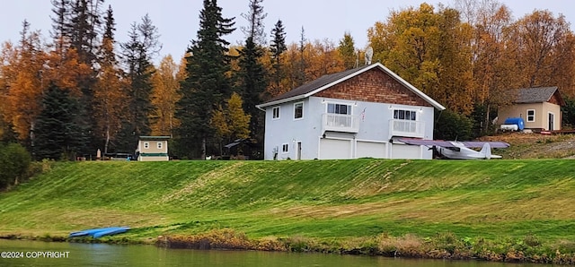 view of side of home featuring a water view, a lawn, a wooded view, and stucco siding