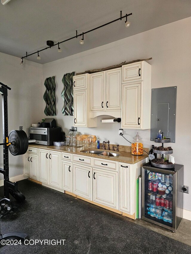 kitchen with beverage cooler, stainless steel microwave, a sink, and electric panel