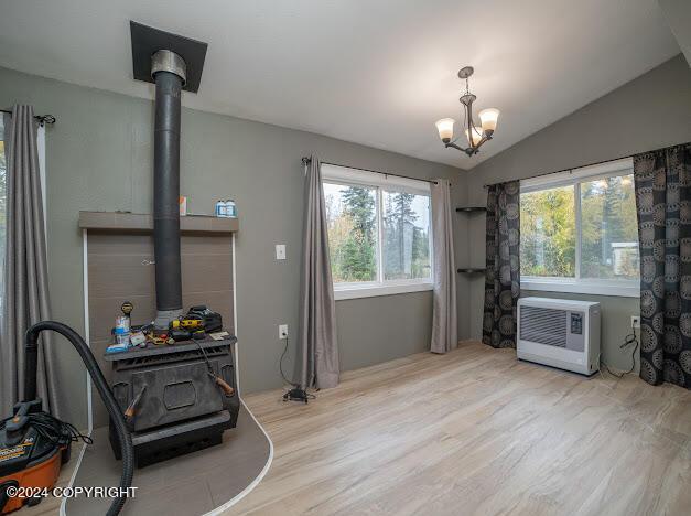 misc room with light hardwood / wood-style floors, vaulted ceiling, heating unit, and a chandelier