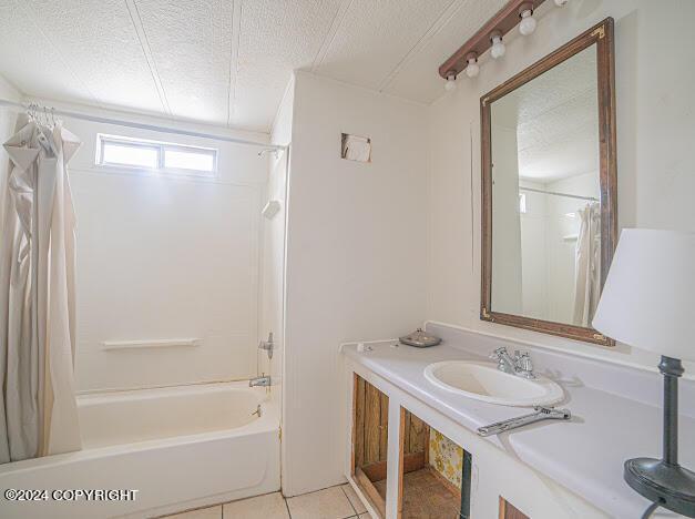 bathroom with vanity, shower / bath combination with curtain, a textured ceiling, and tile patterned flooring