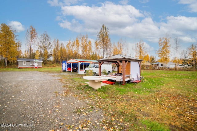 exterior space featuring a gazebo, a lawn, and an outbuilding