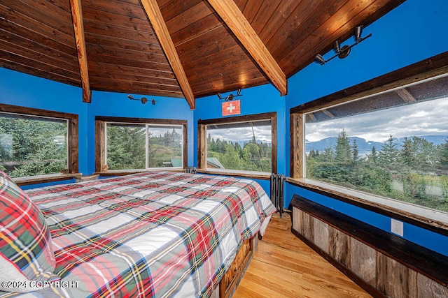 bedroom with lofted ceiling with beams, wood ceiling, and light hardwood / wood-style floors