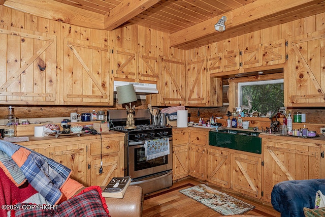 kitchen featuring wood ceiling, wood walls, beam ceiling, stainless steel gas stove, and light hardwood / wood-style floors