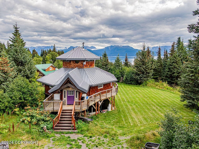 rear view of house with a deck with mountain view and a yard