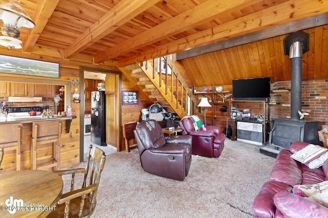 34464 Fishermans Rd, Soldotna, AK 99669 - carpeted living room featuring a wood stove, wood walls, stairs, and wooden ceiling with exposed beams