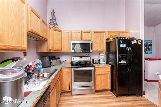 kitchen with light brown cabinets, light hardwood / wood-style flooring, and black appliances