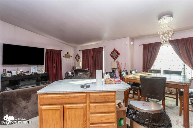 kitchen featuring an inviting chandelier, vaulted ceiling, a center island, and light colored carpet